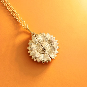 Detailed close-up of golden sunflower locket pendant necklace with opening feature