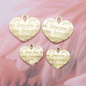 Flat lay of golden heart-shaped pendants with 'you love you' engraving in two sizes