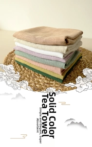 Stack of colorful cotton linen waffle tea towels on a woven mat for kitchen decor