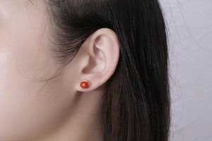 Close-up of vintage red marble pattern stud earrings with gold metal rim on model
