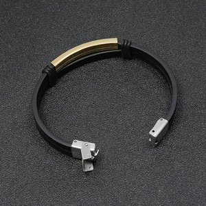 Detail of black silicone wristband with curved gold metal plate and steel clasp