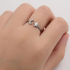Close-up of silver minimalist moon and star open ring worn on a finger