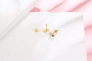 Close-up of cute strawberry stud earrings with pink enamel on a geometric stand