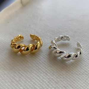 Detailed view of intertwined gold and silver twisted rope rings on beige fabric