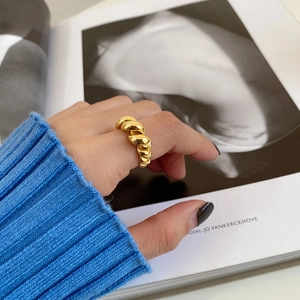 Detail shot of a twisted gold rope ring on a finger over a fashion magazine background