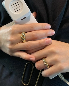 Close-up of double-layered twisted gold rings worn by a model holding a vintage handset