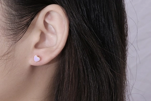 Close-up of minimalist heart-shaped earring in purple enamel with gold-tone metal border