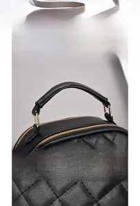 Close-up of black quilted leather handbag showing golden zippers and fine stitching details