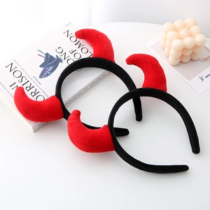 Pair of plush red devil horn headbands for Halloween party decor on a white table