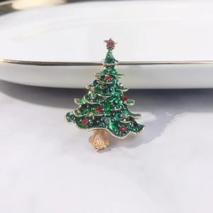 Close-up of a Christmas tree brooch with green enamel inlay and sparkling rhinestones