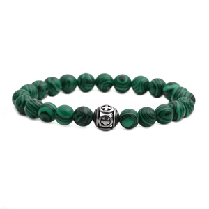 Malachite beaded bracelet with a silver stainless steel hollow cross charm on white background