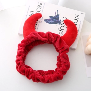 Vue détaillée d'un serre-tête rouge en peluche avec cornes de diable sur fond blanc