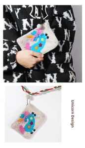 Detail of handmade wool felt unicorn coin purse with colorful embroidery and white pom-pom