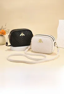Detail of vintage small crossbody bag featuring V-quilted pattern and golden bee decor