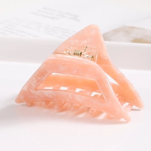 Detail view of pink marble acetate triangular hair claw clip with golden metal spring