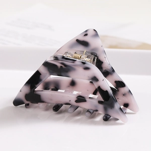Close-up of a cow pattern acetate triangle hair claw clip with golden metal spring