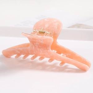 Detailed close-up of the peach marble acetate hair claw clip with golden metal spring