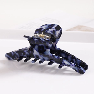Detail of blue and white marble pattern hair claw clip on minimalist white surface
