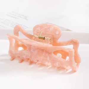 Detail of pink marble acetate hair claw clip with golden metal spring and multi-tooth design