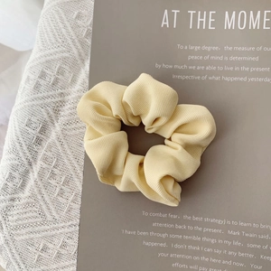 Close-up of light yellow oversized scrunchie with vertical ribbed fabric texture