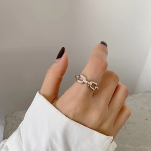 Close-up of minimalist silver geometric chain ring worn on the index finger by a model