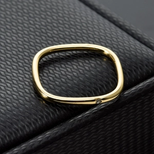 Detailed close-up of a polished gold square bangle with a single embedded crystal
