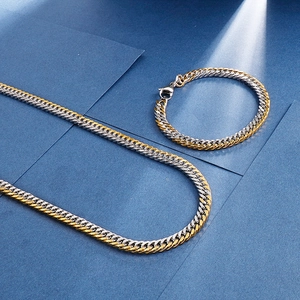 Macro detail of two-tone gold and silver Cuban chain necklace and bracelet set