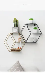 Close-up of hexagonal metal wall shelves in matte gold and black finish with wooden base