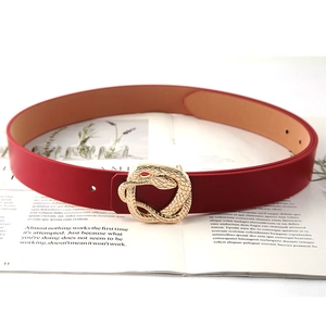 Red leather belt featuring a golden snake-shaped buckle on a lifestyle magazine