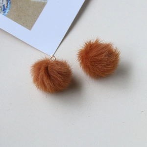 Close-up of fluffy brown plush balls with golden metal rings for DIY jewelry design