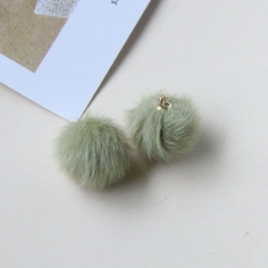 Detail view of two light green plush yarn ball pendants with metal hanging rings for DIY crafts