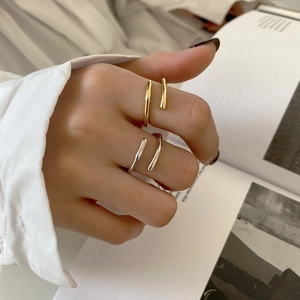 Detail of adjustable gold and silver minimalist wrap rings on model holding a magazine
