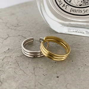 Close-up of minimalist parallel layered open rings in gold and silver finishes
