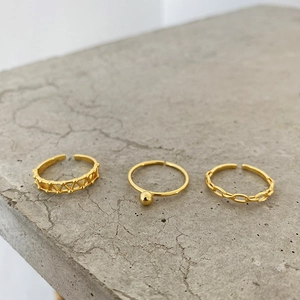 Three-piece gold ring set featuring geometric triangle, ball and chain link designs