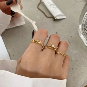 Detailed view of layered gold rings including grid, bead and flat chain textures