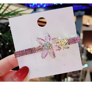 Detail of purple crystal flower hair clip with golden butterfly and rhinestone accents