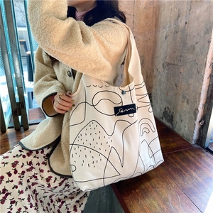 Detail of cream canvas tote bag with black abstract art line drawing and shoulder strap