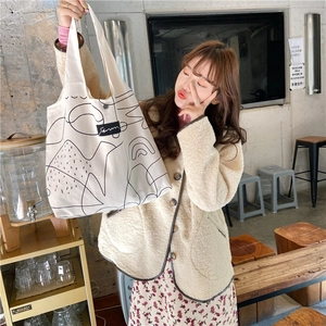 Detail of off-white canvas tote bag with black abstract line art and fabric logo label