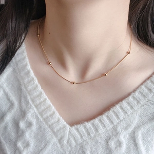 Detail of rose gold bead necklace on model neck with minimalist snake chain design