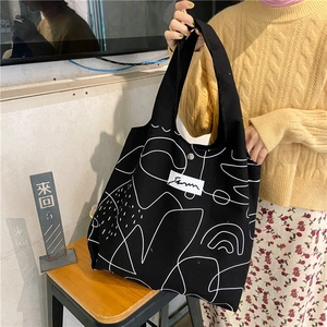 Detail of black canvas tote bag with white abstract lines and secure silver snap button