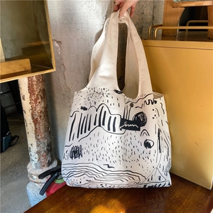 Detail of minimalist cream canvas tote bag featuring black abstract line art and wide handle