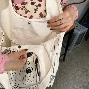 Detail of canvas tote bag showing interior zip pocket and metal snap button closure