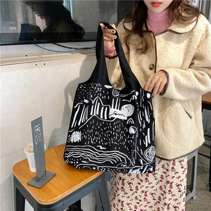 Detail of minimalist black canvas tote featuring white abstract hand-drawn line art
