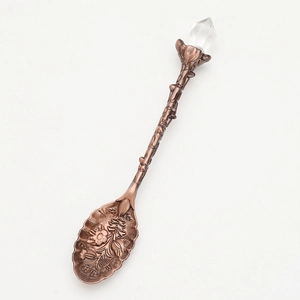 Vintage bronze leaf spoon with branch handle and crystal top on white background