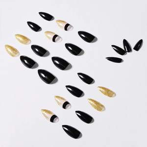 Long stiletto press-on nails featuring black glossy finish and gold glitter gradients