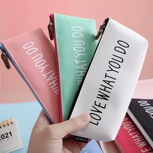 Close-up of hand holding pastel PU leather pencil cases with Love What You Do print