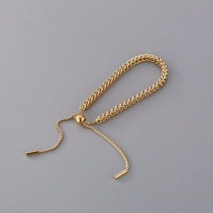 Adjustable golden wheat chain bracelet with minimalist woven texture on grey background