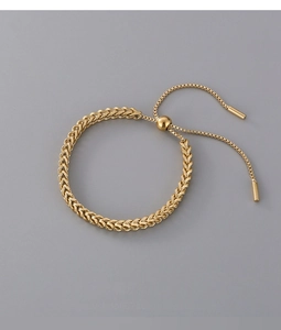 Detailed view of adjustable woven titanium steel bracelet in gold finish on grey background
