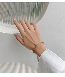 Close-up of golden braided wheat chain bracelet on wrist featuring adjustable design