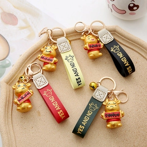 Detail of four colorful bull keychains with leather straps and golden rings in a tray